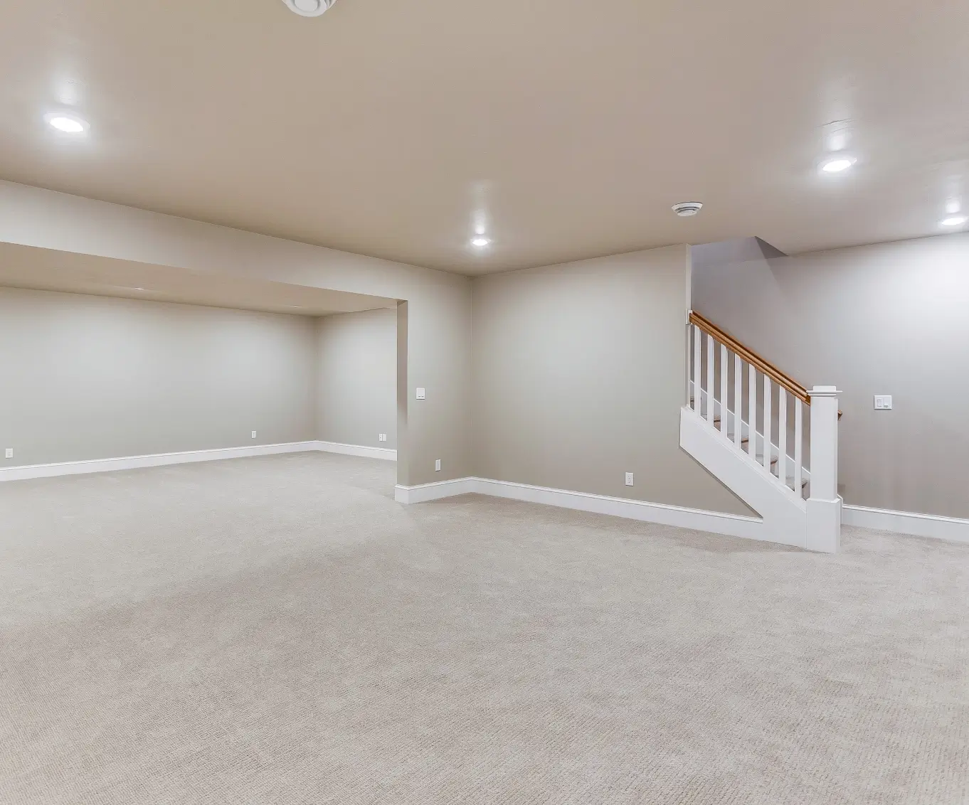 Empty basement with carpet and staircase.