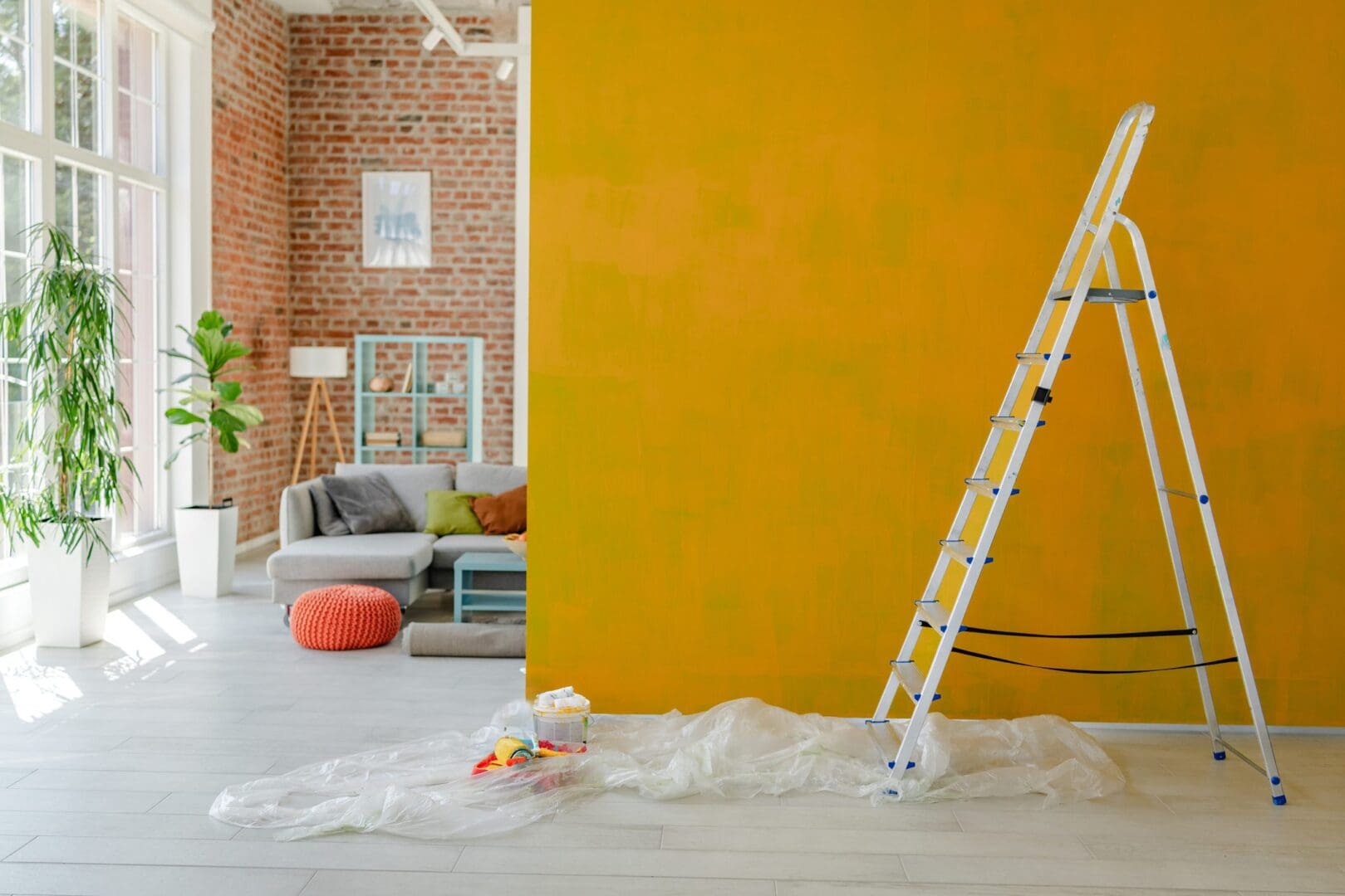 Room in the middle of painting with ladder and drop cloth.